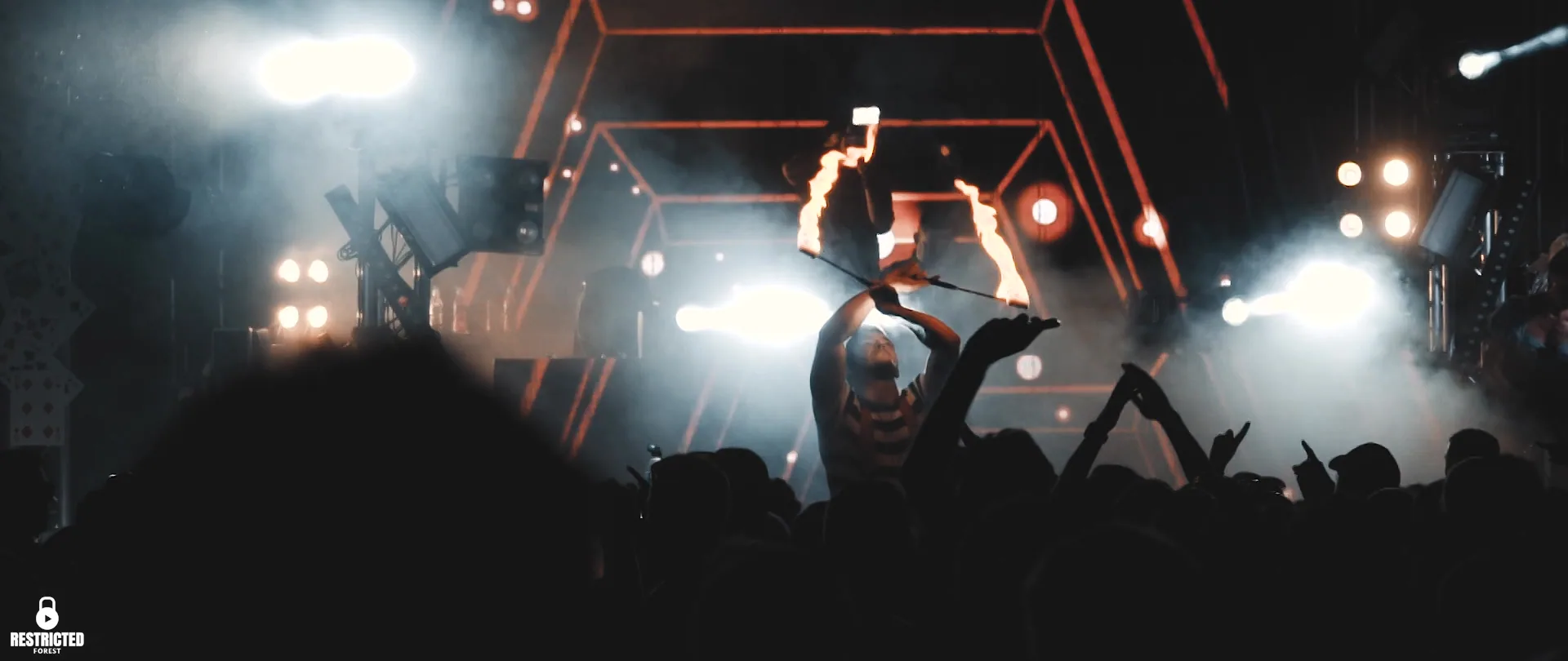 A crowd silhouetted under a bank of white stage beams