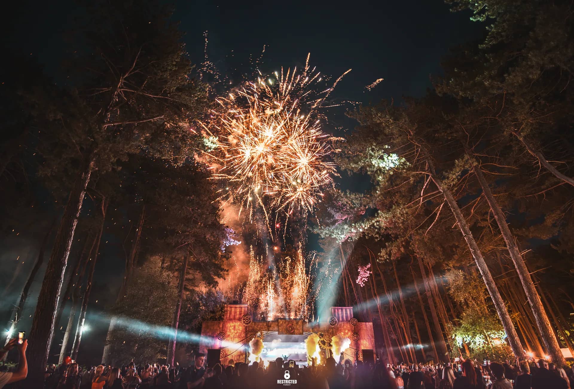 Fireworks bursting above the main stage at night over a full crowd.