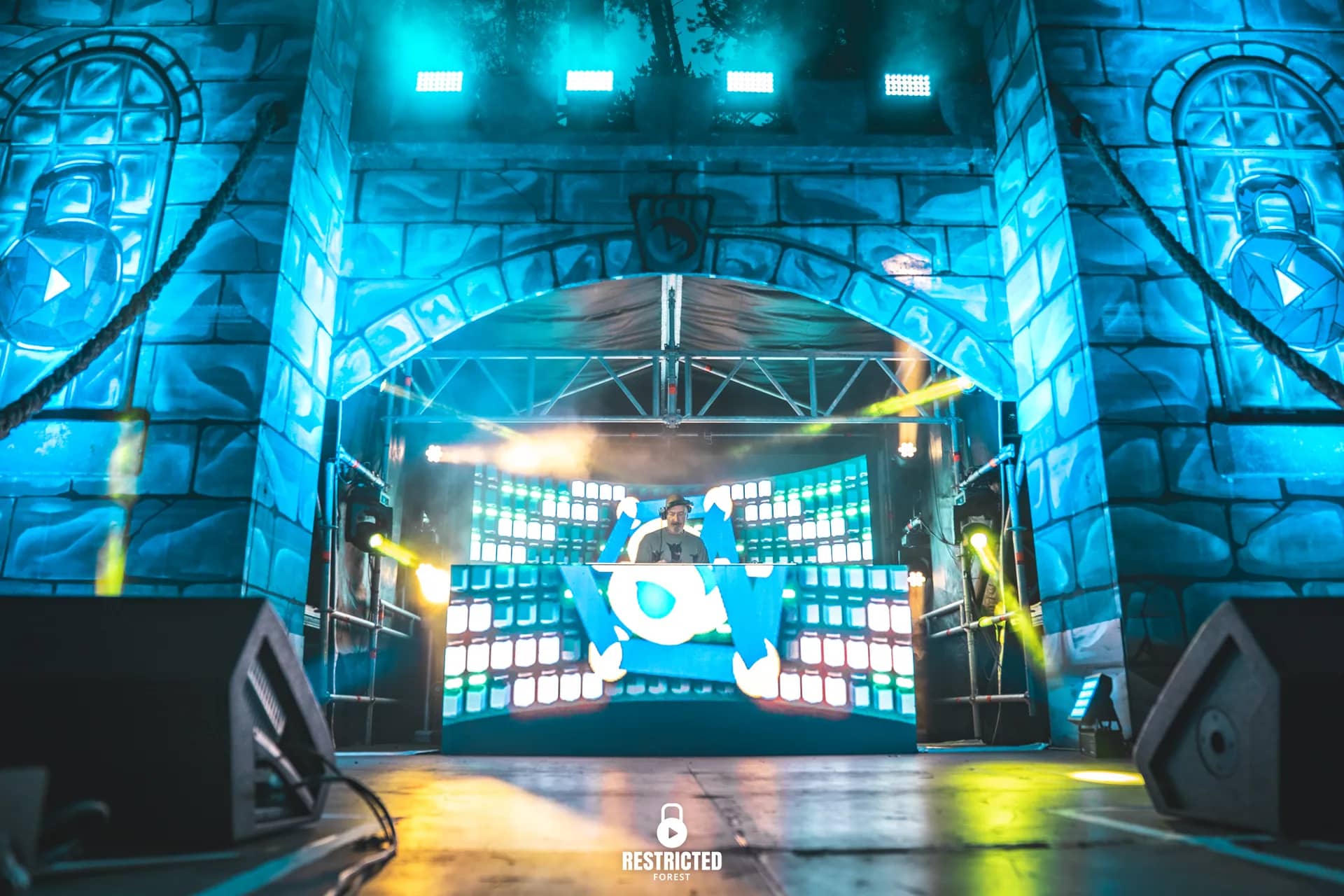 Blue-lit gateway stage with the DJ booth centre and only a scattering of people in front.