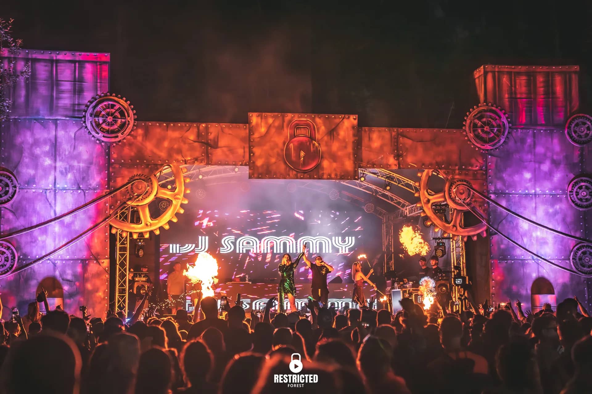 Cog stage in purple and orange at night with the headline name on the screen.