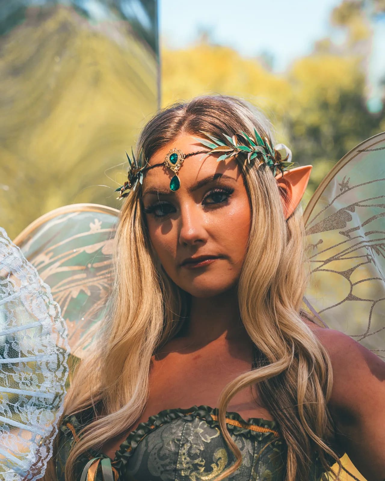 The Bloomkeeper, guardian of the Secret Garden: gossamer wings, a gold leaf headpiece and a green corset, photographed in the pines.