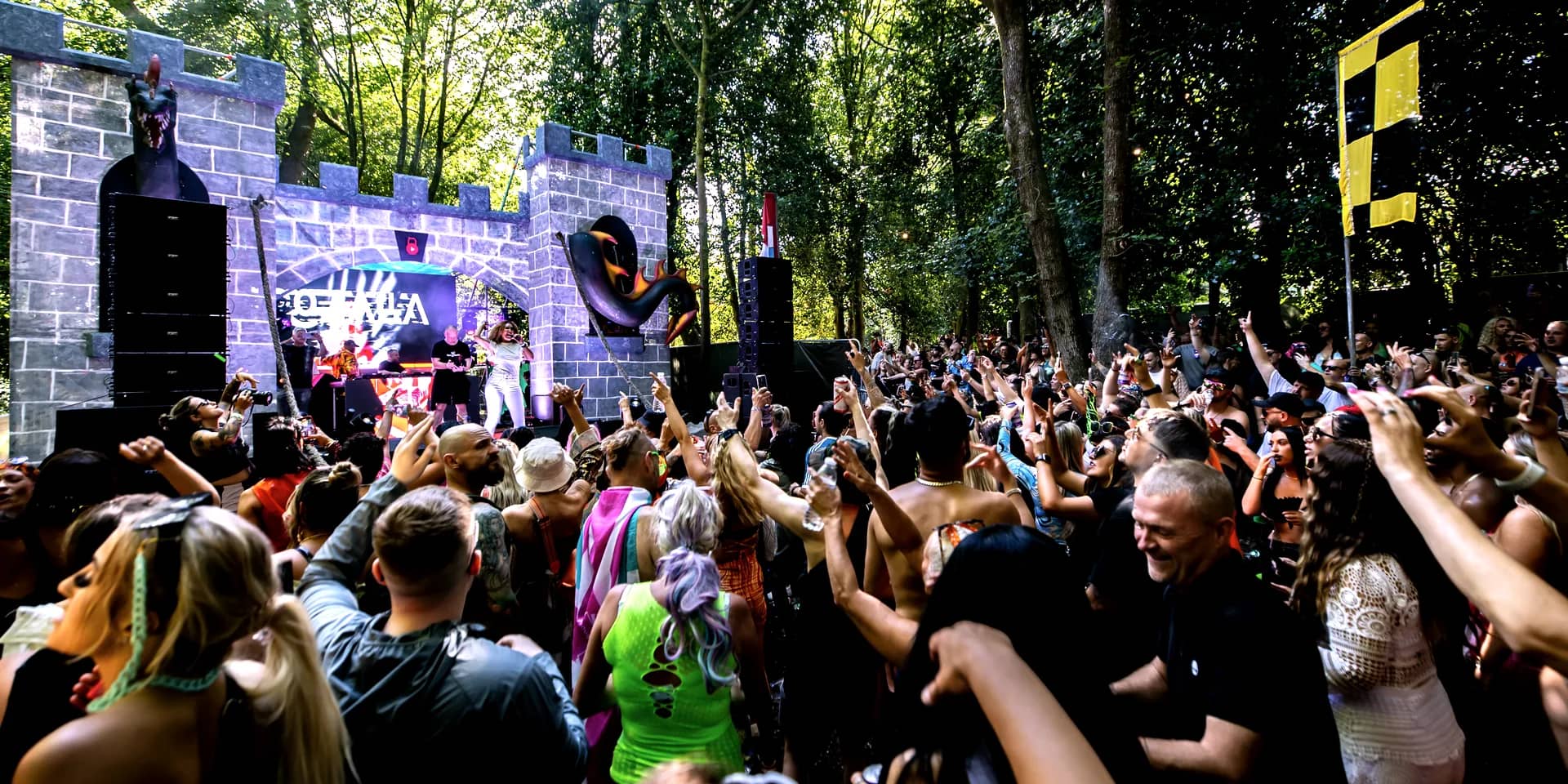 The stone castle stage with the crowd in front and a chequered flag flying above the towers.