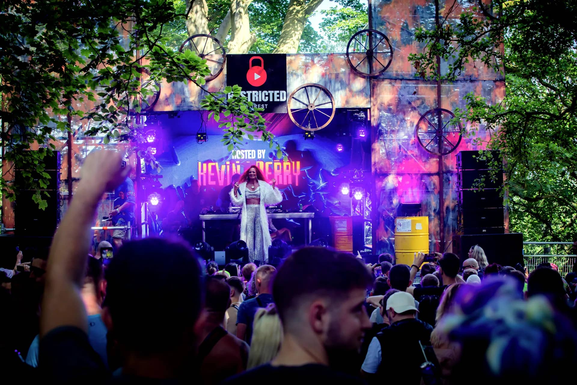 The cog stage lit purple with a performer at the decks and the crowd in front, a cog wheel on each tower.