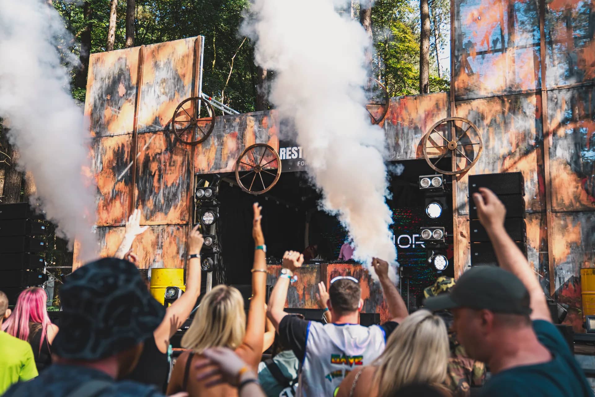 The cog stage with white smoke jets firing, the crowd close in front in daylight.