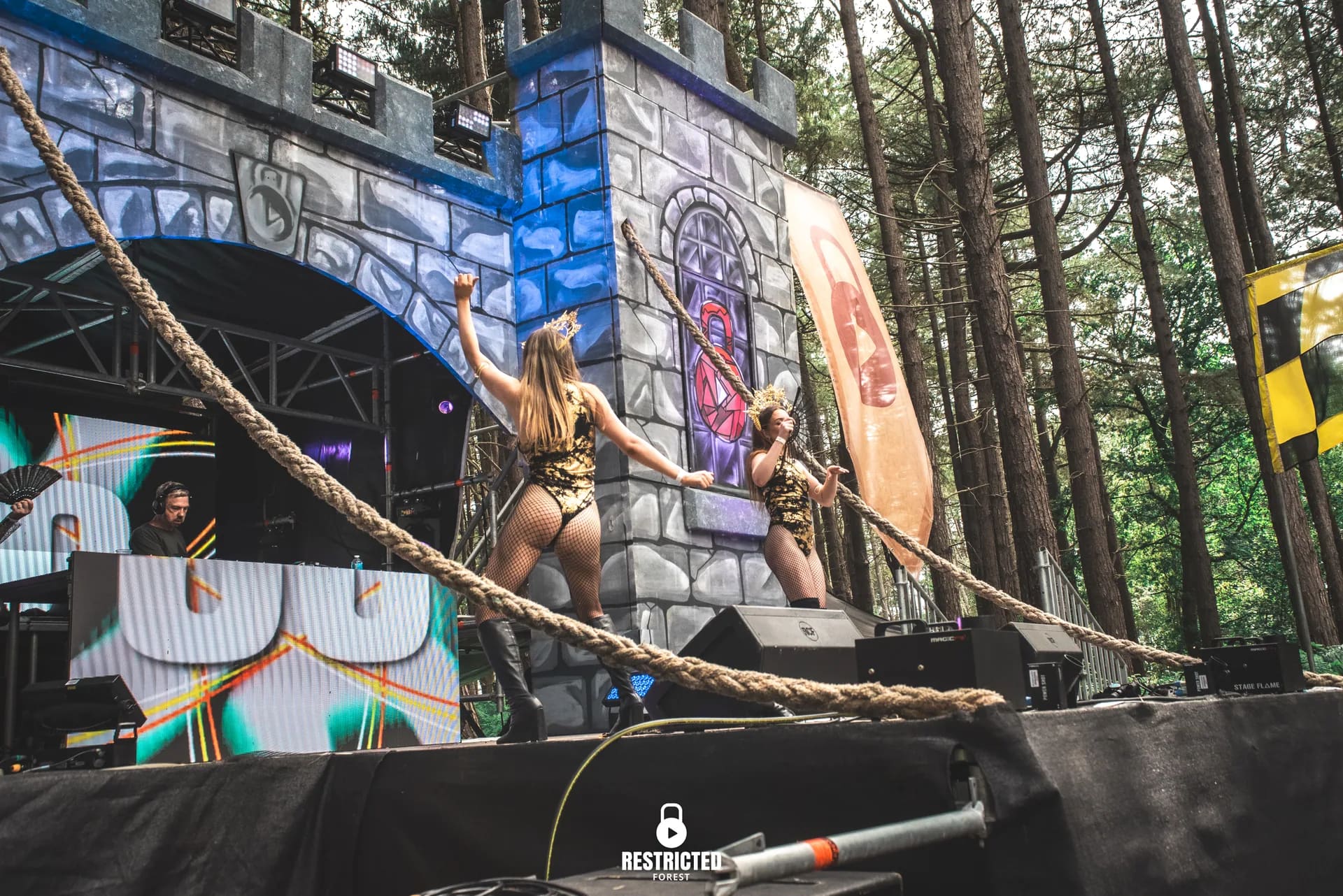 Dancers performing on a graffiti stage in full daylight, rope prop across the frame